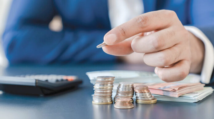 Businessman,Holding,Euro,Cents,Coins,Dollar,Bills,On,Table,With